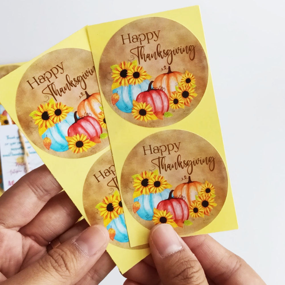 Hand holding rustic pumpkin and sunflower Thanksgiving stickers on backing sheet