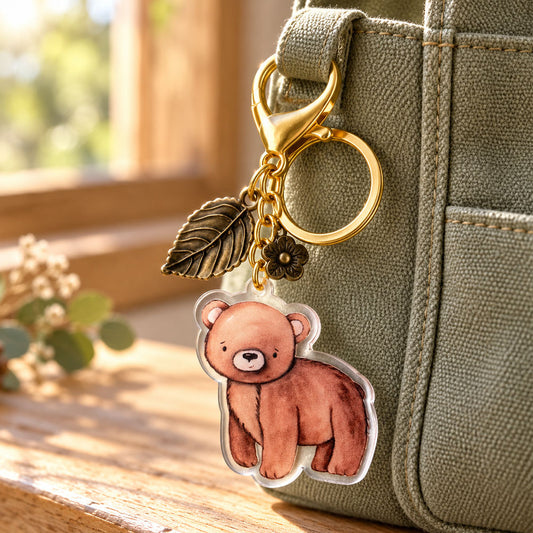Brown bear acrylic keychain clipped to an olive green bag with a gold-tone lobster clasp