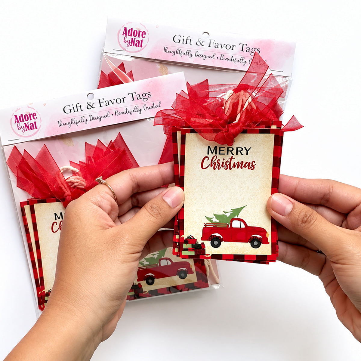 Hands holding a vintage red truck Christmas gift tag, showing the design and red ribbon