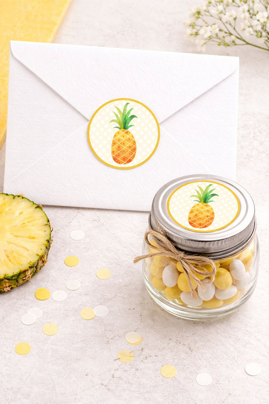 Pineapple round sticker used as envelope seal and favor jar label on light neutral tabletop background