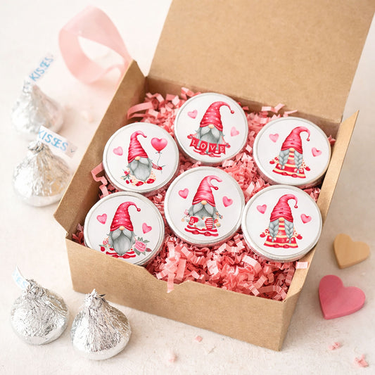 Valentine’s Day gnome candy stickers on Hershey’s Kisses chocolates arranged in a kraft gift box with pink crinkle paper, festive Valentine candy favors