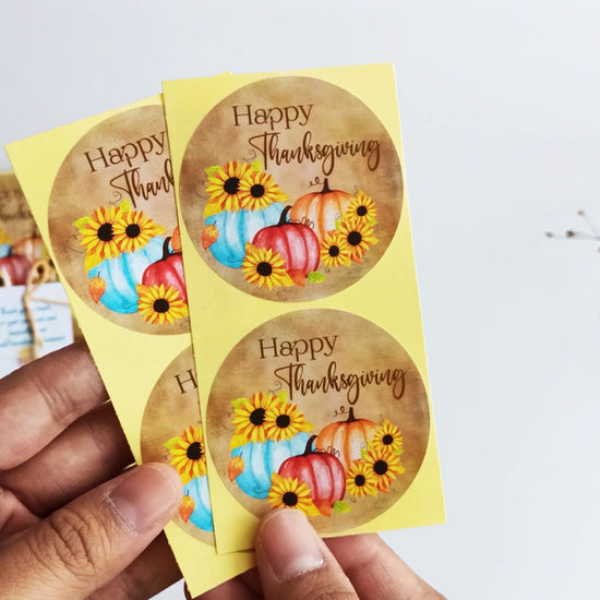 Hand showing rustic pumpkin and sunflower Thanksgiving stickers for fall party favors